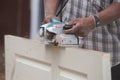 Worker planing a wood of door with electric plane