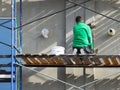 A worker plastering a building facade while standing on a scaffold. Construction work on the construction of a high-rise building Royalty Free Stock Photo