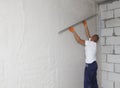 Worker plastering house walls, finishing walls. Wall screeding. Plastering walls techniques