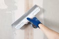 Worker plastering wall with putty knife indoors, closeup Royalty Free Stock Photo