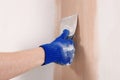 Worker plastering wall with putty knife indoors, closeup Royalty Free Stock Photo