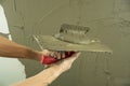 A worker plasters the wall with a spatula and applies a cement mix solution. The repairman lays the plaster on the drywall.