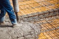 worker pouring cement or concrete with pump tube. Reiforced steel bars and rods