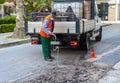 Worker pours water on the milled asphalt