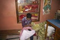 worker of a prayer item shop stitching organic sal leaf to make holy disposible bowl to carry religious hindu offering