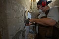 A worker prepares for a renovation, using a hammer drill to remove old plaster and cement from a wall wearing protective ear Royalty Free Stock Photo