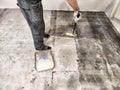 Worker preparing the floor by priming it before tile installation in a renovation project Royalty Free Stock Photo