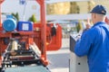 Worker pressing buttons on CNC machine control board in factory