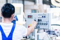 Worker pressing buttons on CNC machine in factory Royalty Free Stock Photo