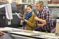 Worker in printing house showing prints to client