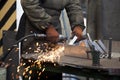 Worker processing metal, lots of sparks, against factory industrial interior background