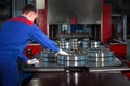 A worker in the production of bearings manually removes the finished product after canning it with engine oil. Photo without a