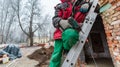 Worker in protect gloves is holding the hand screwdriver on the ladder in construction site. Concept of using of