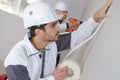 Worker protecting batten moulding with masking tape before painting Royalty Free Stock Photo
