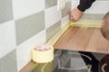 Worker protecting countertop in kitchen with masking tape before starting construction repairs with ceramic tiles