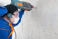 A worker in protective clothing, engaged in dismantling concrete walls , a drill, there is a place for the inscription