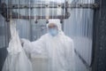 Worker In Protective Mask And Suit Behind Plastic Wall At Lab