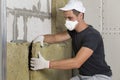 Worker in protective respirator mask insulating rock wool insulation in wooden frame for future house walls for cold barrier. Com Royalty Free Stock Photo