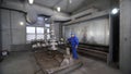 Worker in protective respirator paints oil and gas wellhead tree equipment with spray gun in spray booth. Equipment for