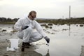 Worker in a protective suit examining pollution