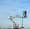 Worker with protective suits on aerial platform of cherry pickers does maintenance on public lighting