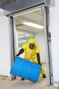 Worker in protective uniform rolling barrel