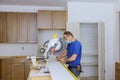 Worker protects himself from covid-19, man cut using circular saw rotating saw cutting wooden installation of in the kitchen of Royalty Free Stock Photo