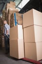 Worker pulling trolley with boxes in warehouse Royalty Free Stock Photo