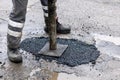 Worker pushing bitumen asphalt in the hole. road repair and maintenance