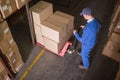 Worker pushing trolley with boxes in warehouse