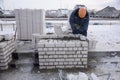 A worker puts bricks in cement in straight rows, makes a concrete wall. Royalty Free Stock Photo