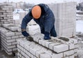 A worker puts bricks in cement in straight rows, makes a concrete wall. Royalty Free Stock Photo