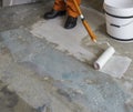Worker puts primer with roller on concrete floor. Apartment unde Royalty Free Stock Photo