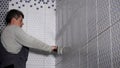 Worker putting fugue on wall tiles joints in bathroom. Man grouting tiles