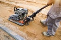 Worker rams the ground with a vibrating machine