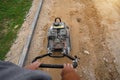 Worker rams the ground with a vibrating machine. Top view