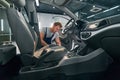 Worker readies car carpet, mat for cleaning interior in auto service