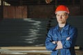 Worker in a red cap and uniform stands against the backdrop of t Royalty Free Stock Photo