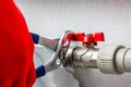 A worker in red gloves with a wrench, installs a shut-off valve on the heating radiator pipe Royalty Free Stock Photo