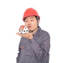 Worker in red hard hat kisses small house model in hand Royalty Free Stock Photo