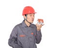 Worker in red hard hat kisses small house model in hand Royalty Free Stock Photo