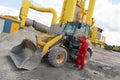 Worker in red uniform getting in to buldozer at construction site