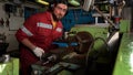 Worker in red uniform operating in manual lathe in metal big workshop Royalty Free Stock Photo