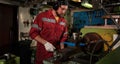 Worker in red uniform operating in manual lathe in metal big workshop Royalty Free Stock Photo