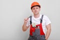 Worker in red uniform, protective hard hat holding bundle of dollars, cash money on white background. Male worker for Royalty Free Stock Photo