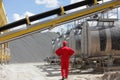 Worker in red uniform at tanks with asphalt