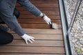 Worker refinishing wood, hand painting wooden deck floor with wood protection oil