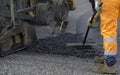 Worker regulate tracked paver laying asphalt heated to temperatures above 160 ÃÂ° pavement on a runway