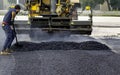 Worker regulate tracked paver laying asphalt heated to temperatures above 160 ÃÂ° pavement on a runway