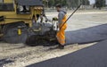 Worker regulate tracked paver laying asphalt heated to temperatures above 160 ÃÂ° pavement on a runway